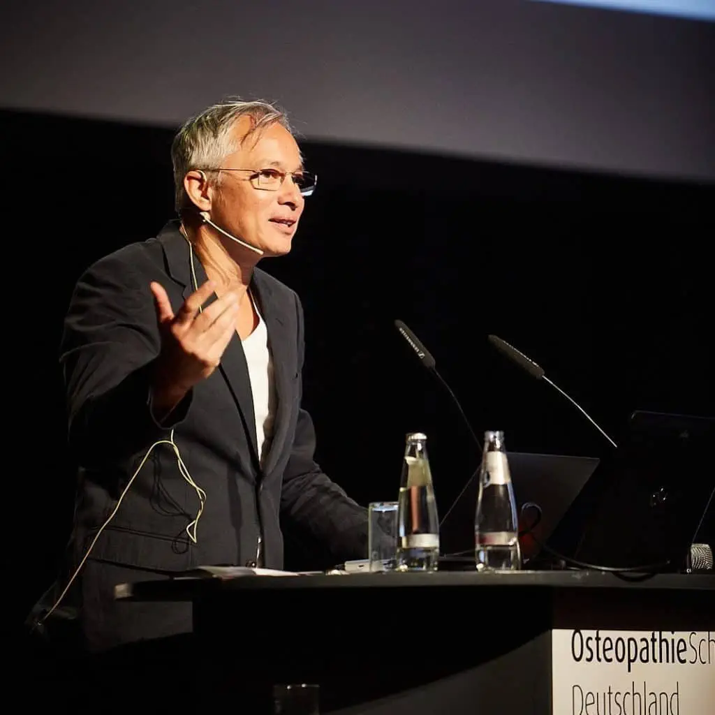 Ein Mann hält eine Rede zum Thema Kinderosteopathie auf einer Konferenz in Hamburg, Deutschland.