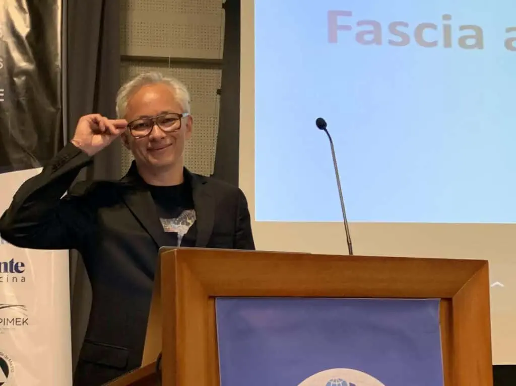 Ein Mann hält auf einem Podium einen Vortrag über Osteopath Hamburg.