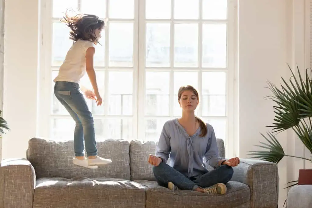 Eine Mutter und ihre Tochter, die Sportosteopathie praktizieren, nehmen an einer friedlichen Meditationssitzung auf einer Couch teil.