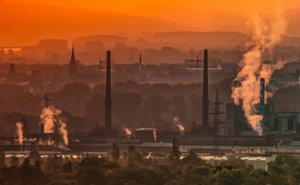Eine Fabrik bei Sonnenuntergang, die in der Abenddämmerung Rauch ausstößt.