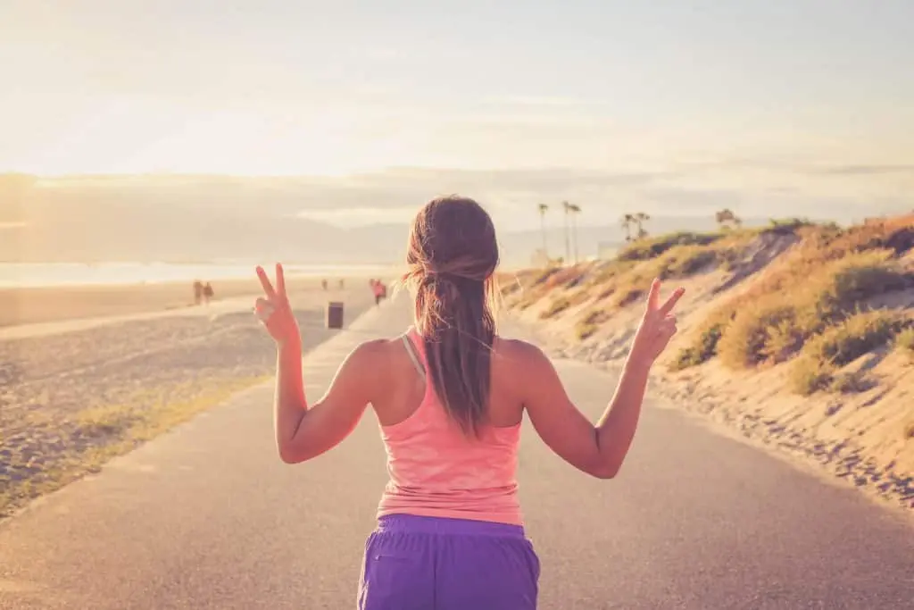 Eine Frau genießt einen Lauf am Strand bei Sonnenuntergang.
