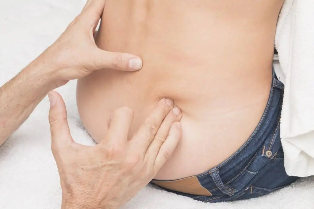 Eine Frau erhält von einem Sportosteopathie-Praktizierenden eine Rückenmassage.