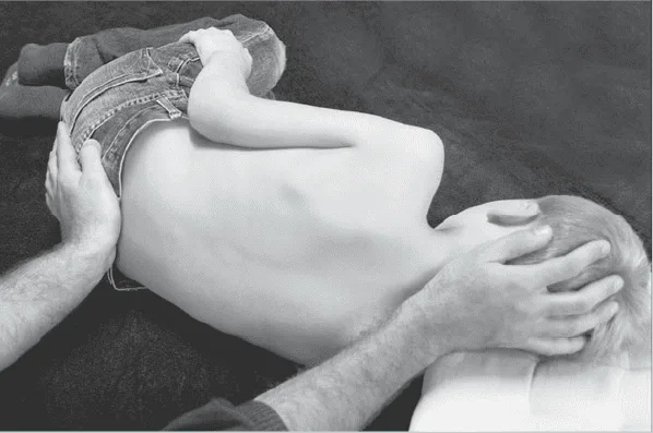 Ein Kind in Hamburg liegt mit den Händen auf dem Rücken auf dem Boden und wird osteopathisch behandelt.
