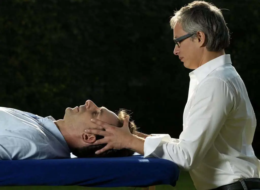 Ein Mann erhält bei einem Osteopathen in Hamburg eine entspannende Kopfmassage von einem anderen Mann.