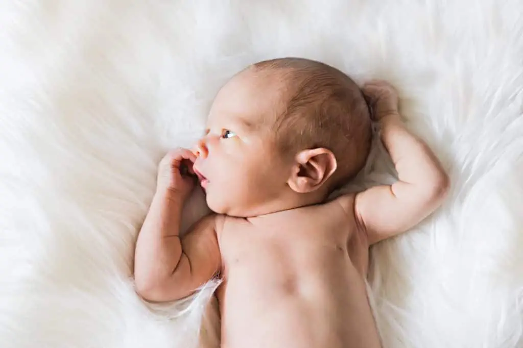 Ein neugeborenes Baby schläft friedlich auf einer weichen weißen Felldecke.