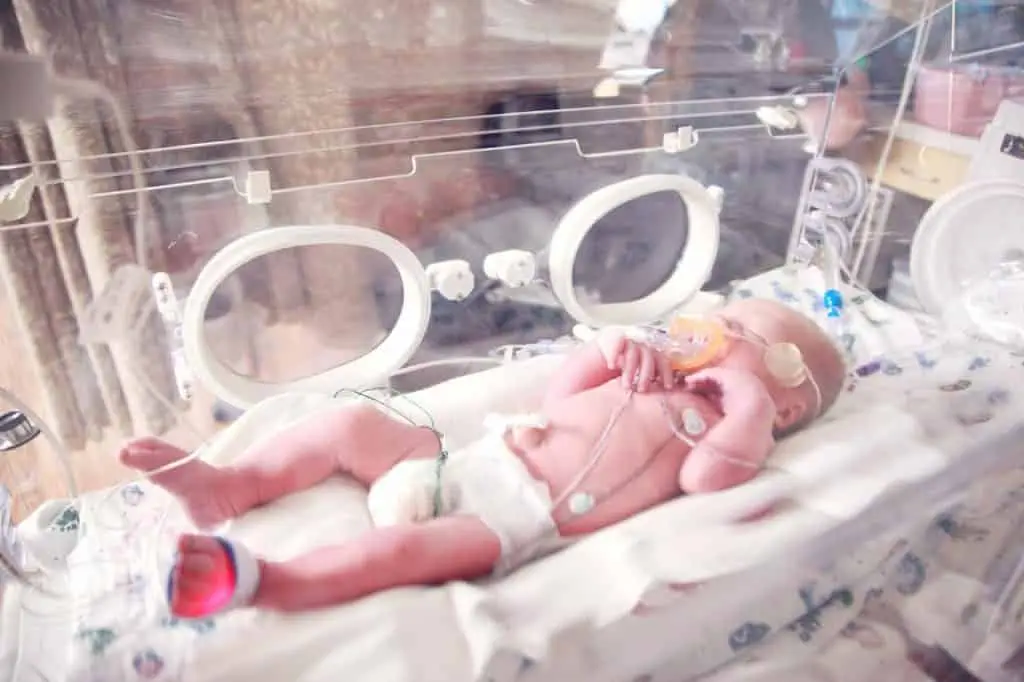 Ein Baby liegt mit einem Schnuller in einem Brutkasten und wird von einem erfahrenen Osteopathen in Hamburg betreut.
