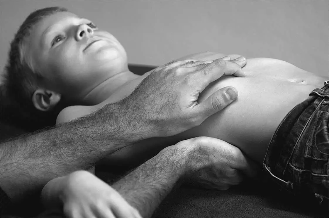 Ein Schwarz-Weiß-Foto eines kleinen Jungen, der auf dem Bauch liegt und sich einer osteopathischen Behandlung unterzieht.