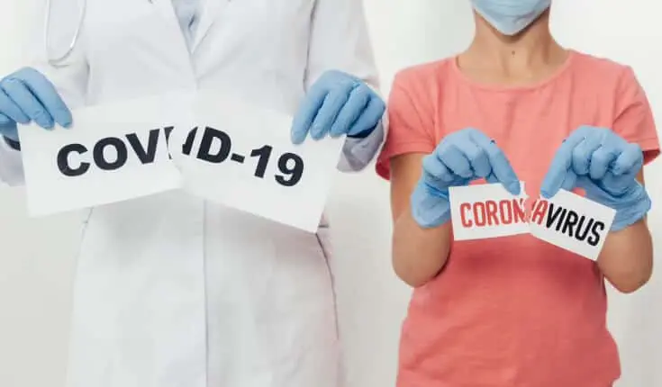 Zwei Menschen halten Schilder mit der Aufschrift „Covid-19“ in Hamburg.