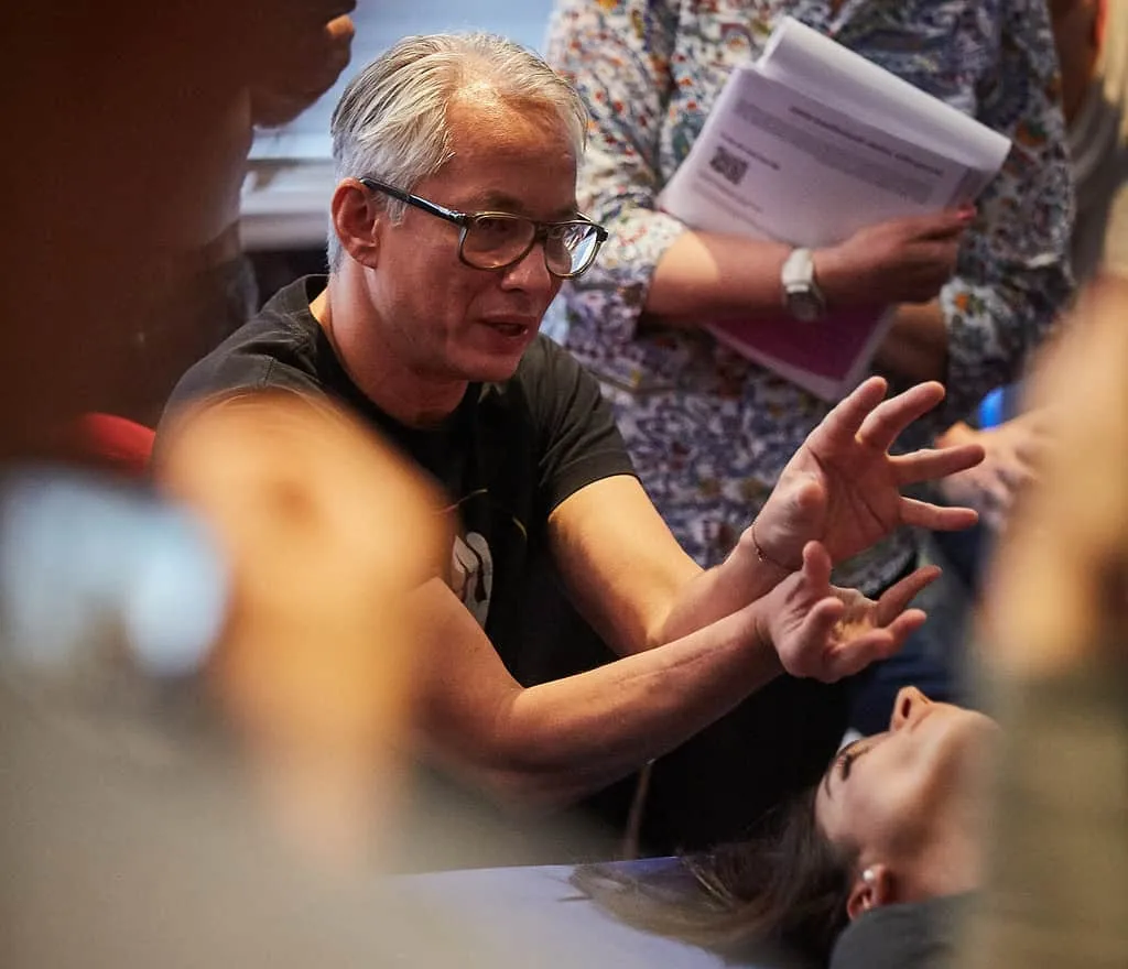 Ein asiatischer Mann übt Sportosteopathie bei einer Frau aus, indem er sanft ihren Kopf berührt.