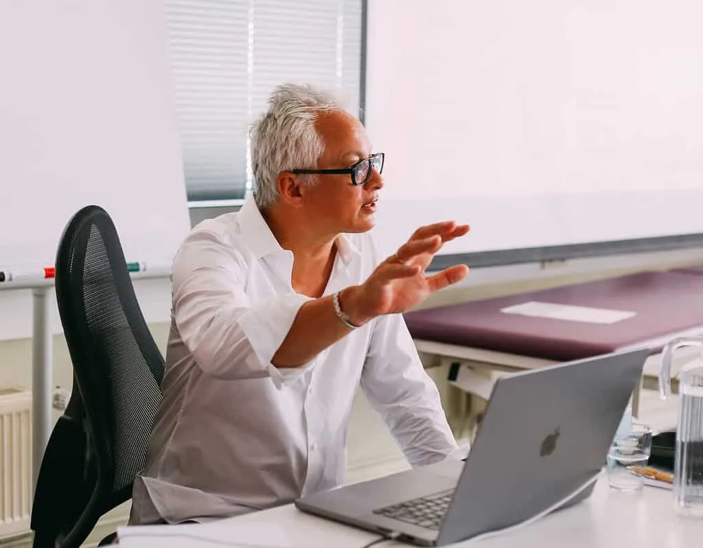Ein Mann sitzt an einem Schreibtisch mit einem Laptop vor sich und arbeitet an seinem Osteopathie-Hamburger Geschäft.