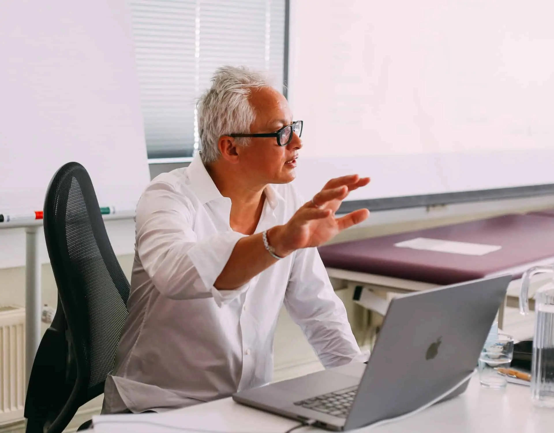 Ein Mann sitzt an einem Schreibtisch mit einem Laptop vor sich und arbeitet an seinem Osteopathie-Hamburger Geschäft.