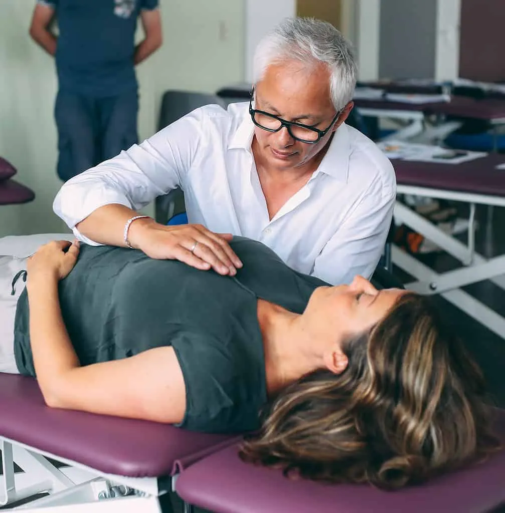 Eine Frau wird von einem Arzt für Kinderosteopathie untersucht.