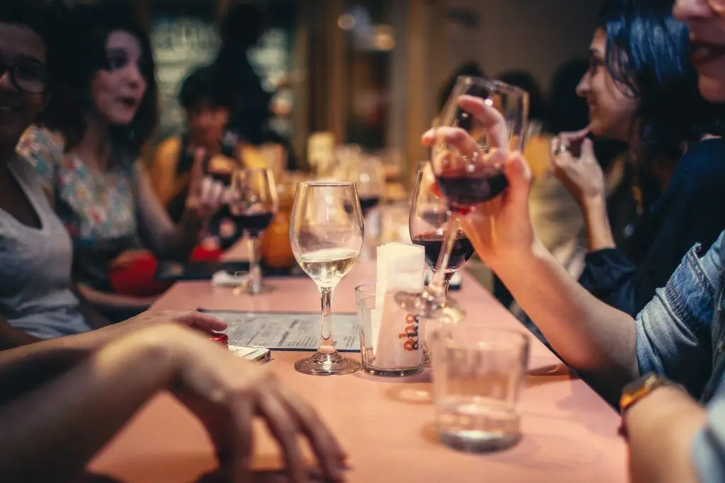 Eine Gruppe von Menschen genießt Wein in einem Restaurant, Osteopathie Hamburg