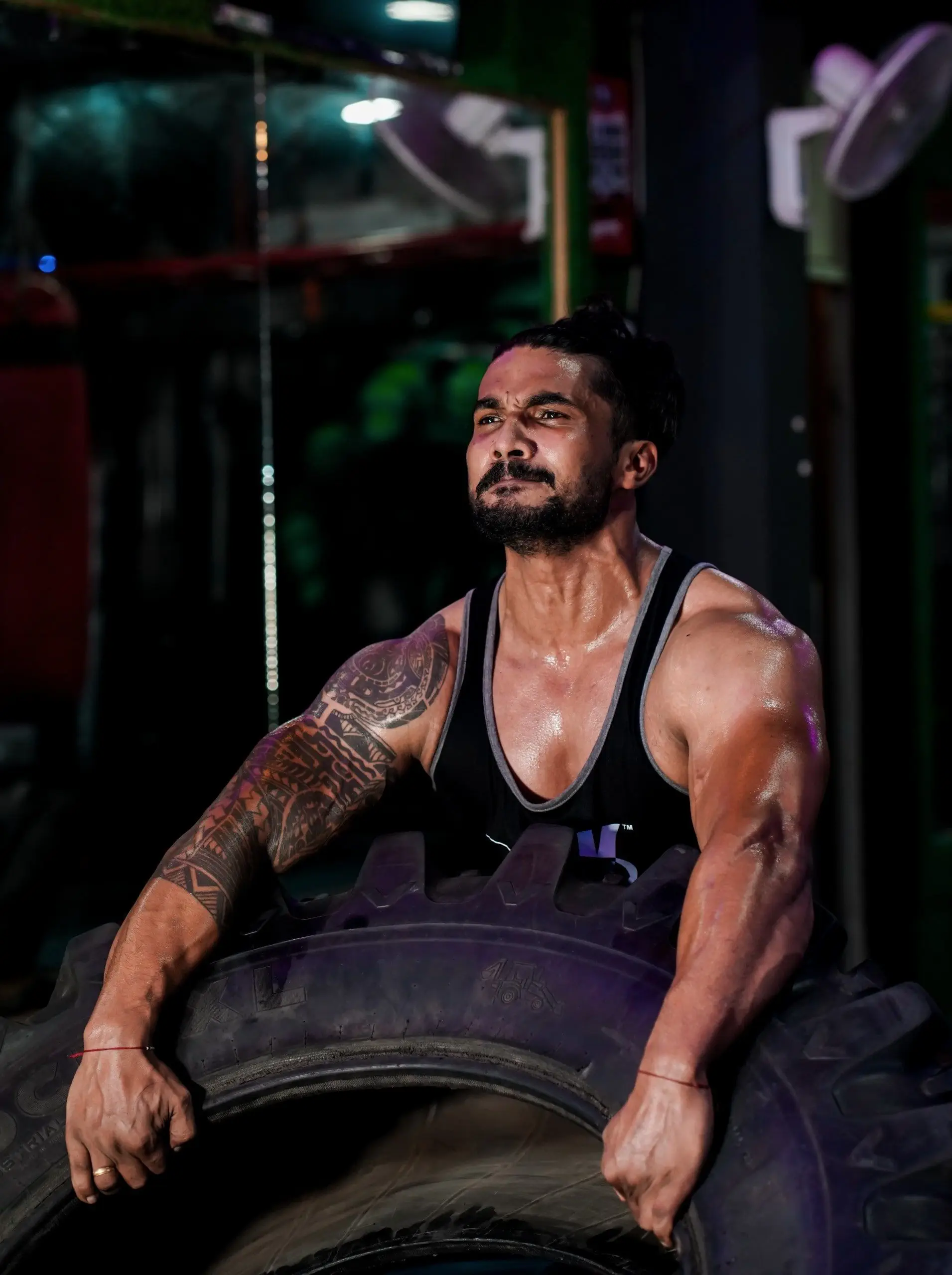 Ein Mann sitzt auf einem Reifen in einem Fitnessstudio und praktiziert Sportosteopathie.